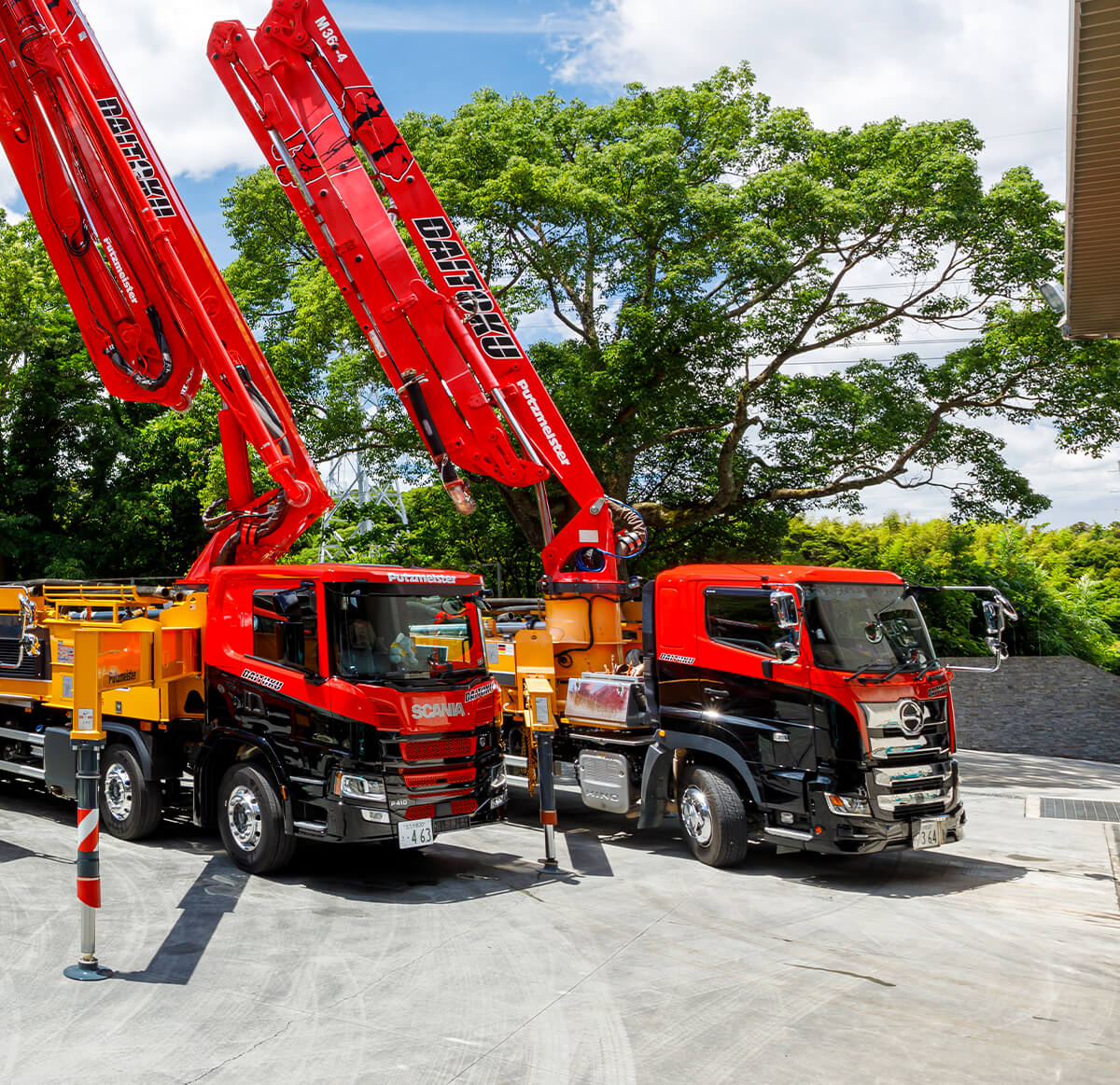 DAITOKUの赤い大型建設車両が2台並んでいる景色。